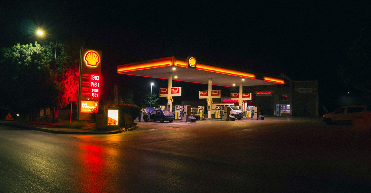 A gas station with glowing neon lights at night, showcasing a calm urban scene.