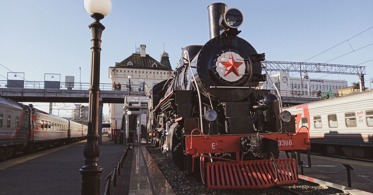 Historic steam train with Soviet star at an outdoor station under a clear sky.