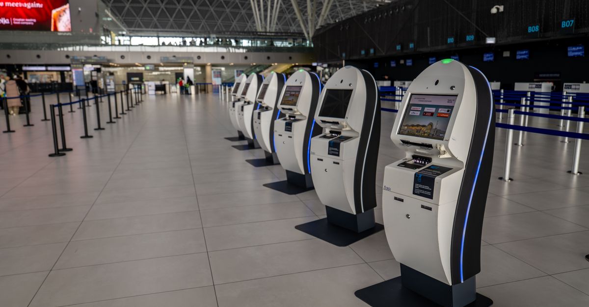 Wide view of an airport terminal in Zagreb featuring self-service check-in kiosks.