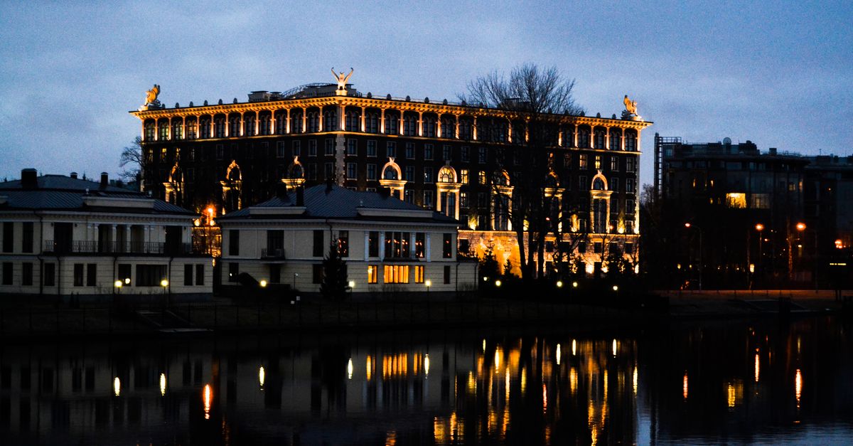 A beautifully illuminated building reflects on a calm body of water at night, capturing serene architectural elegance.