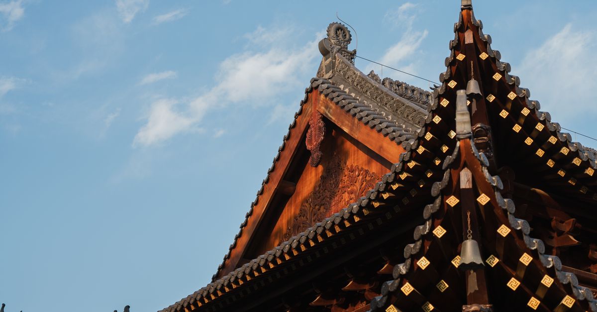 Detailed view of a traditional Chinese temple roof under a clear blue sky.