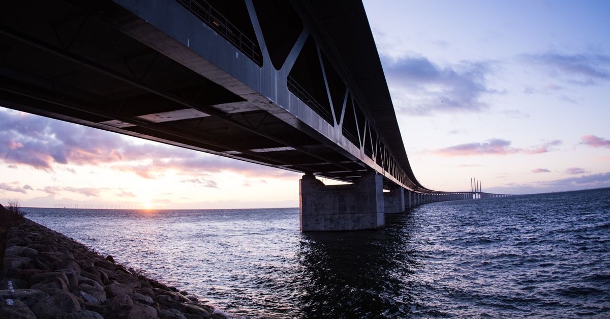 Wide-angle shot of the Öresund Bridge at sunset, showcasing architectural beauty over water.