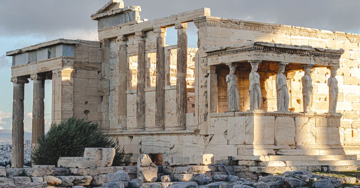 Ancient Erechtheion temple with caryatids at the Acropolis in Athens, Greece, illuminated by sunlight.