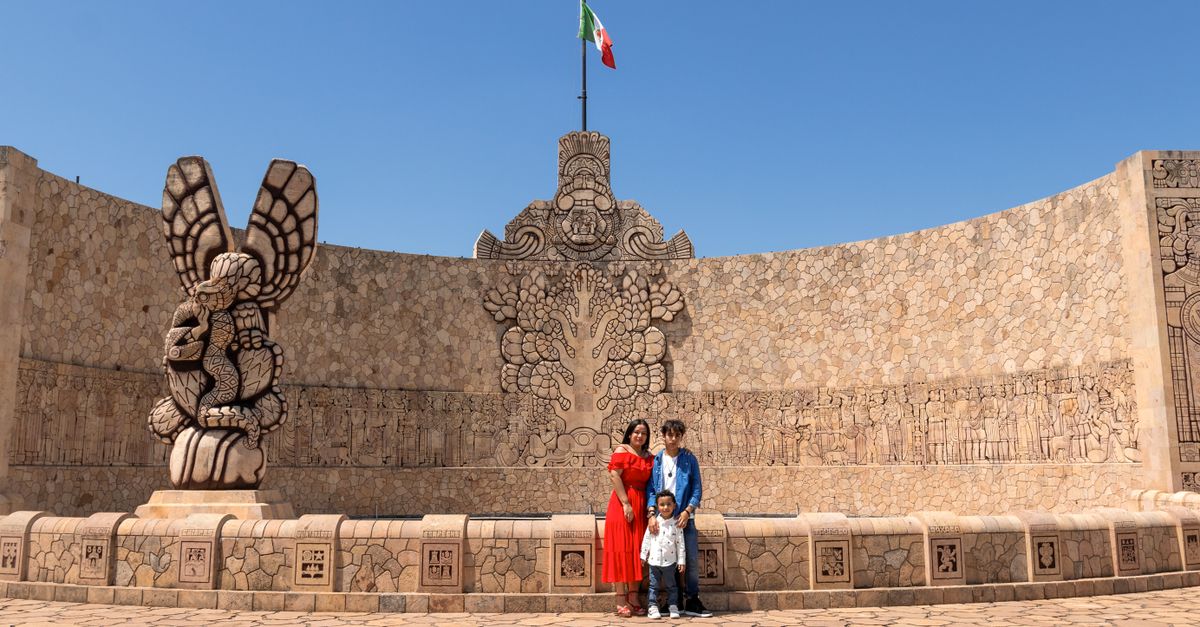 A family poses at the Monumento a la Patria in Mérida, Yucatán with the Mexican flag.