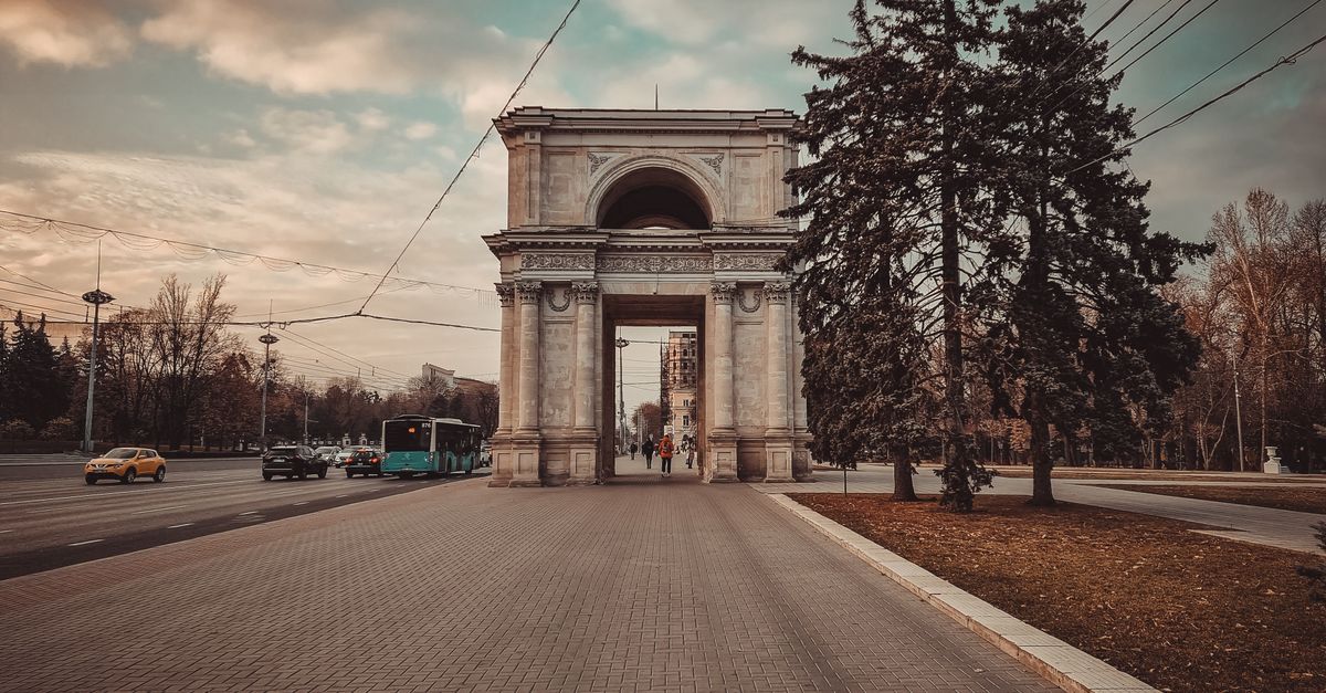 Historic Triumphal Arch in Chișinău, Moldova. A picturesque monument surrounded by a city street scene.