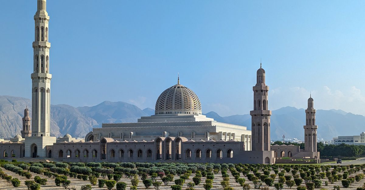 Sultan Qaboos Grand Mosque with its striking minarets against a clear blue sky in Muscat, Oman.