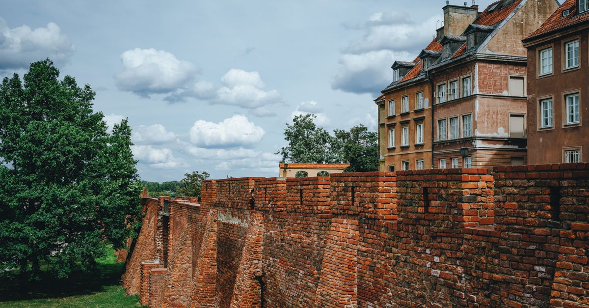 A scenic view of a historic brick wall in the Old Town of Warsaw, Poland with residential buildings.