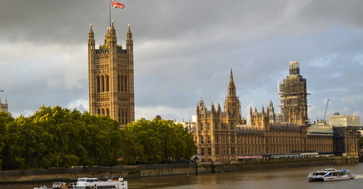 Exterior of the Houses of Parliament near river with steamboats on cloudy foggy day
