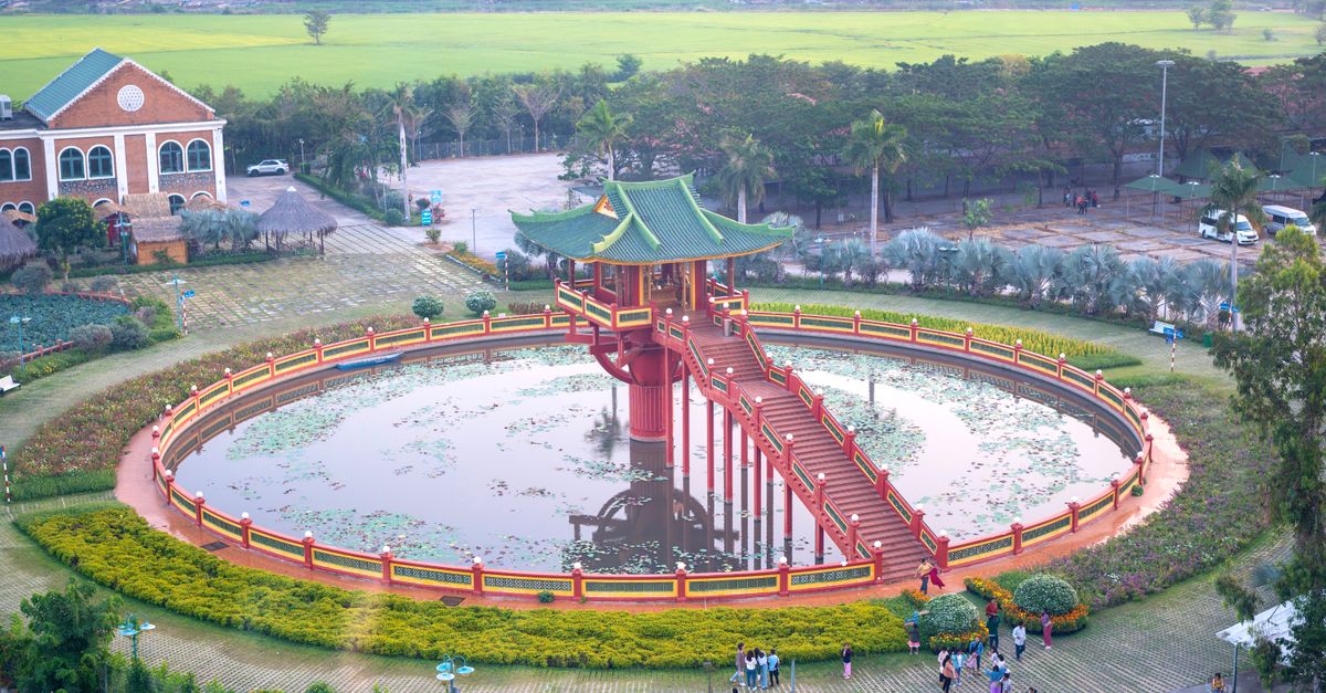 Aerial view of a Vietnamese pagoda surrounded by a pond and green landscape.