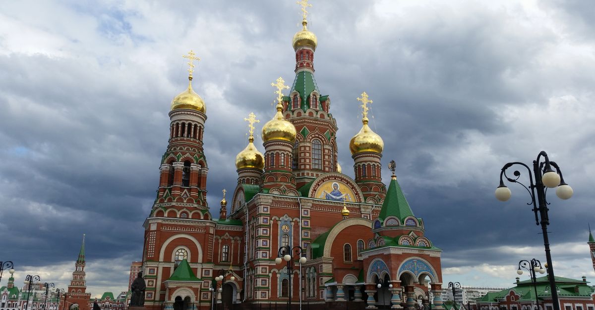 Orthodox cathedral with golden domes against a dramatic cloudy sky in Yoshkar-Ola, Russia.