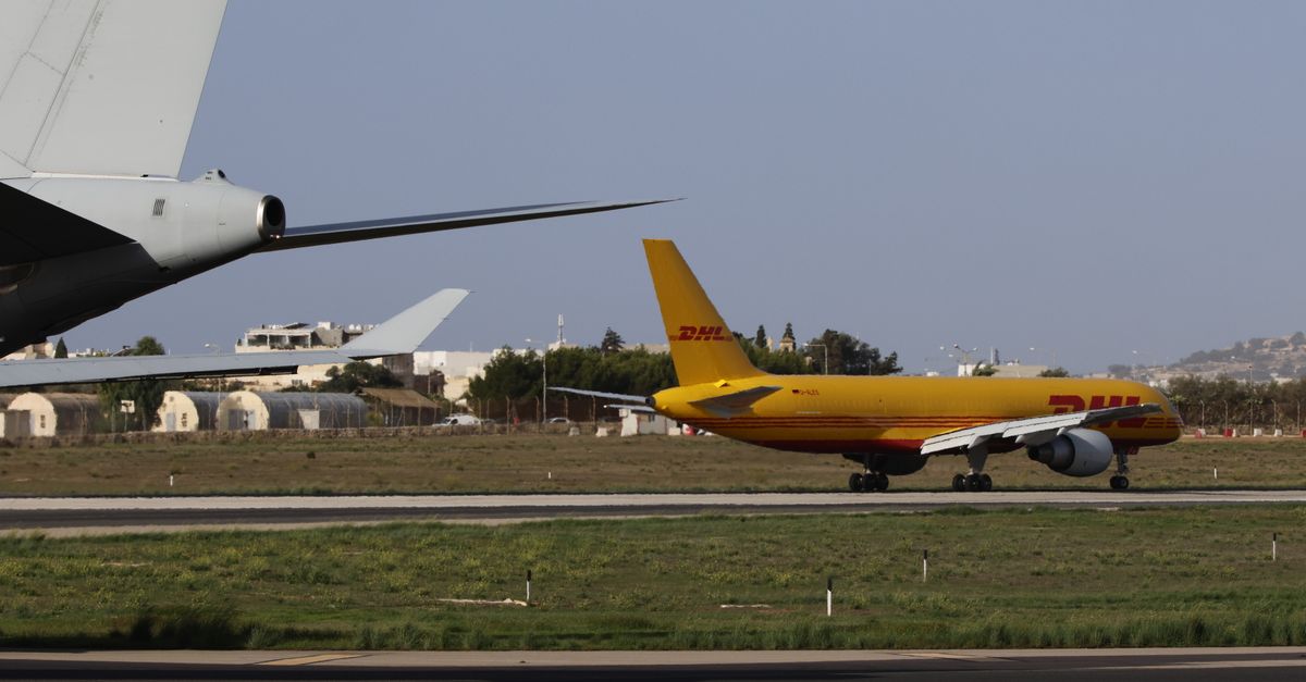 A DHL cargo plane taxiing on an airport runway during daylight.
