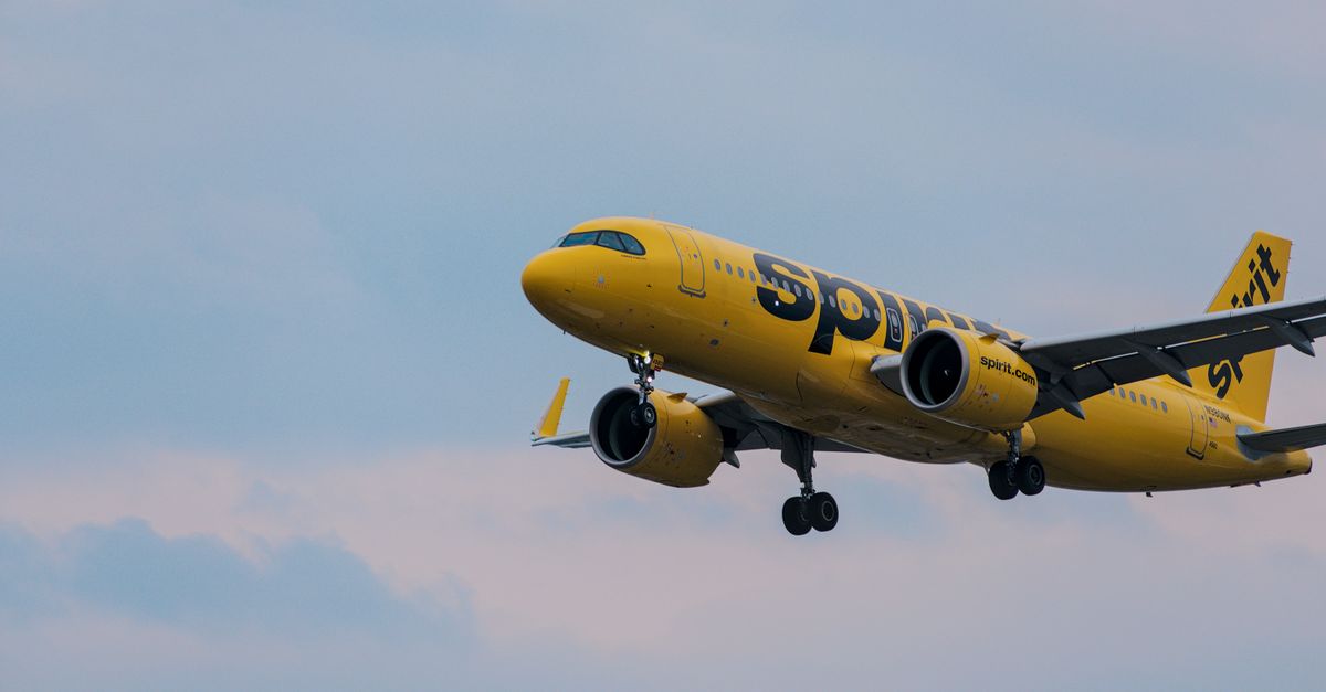 A Spirit Airlines yellow jet in flight over Atlanta, showcasing aviation and travel.