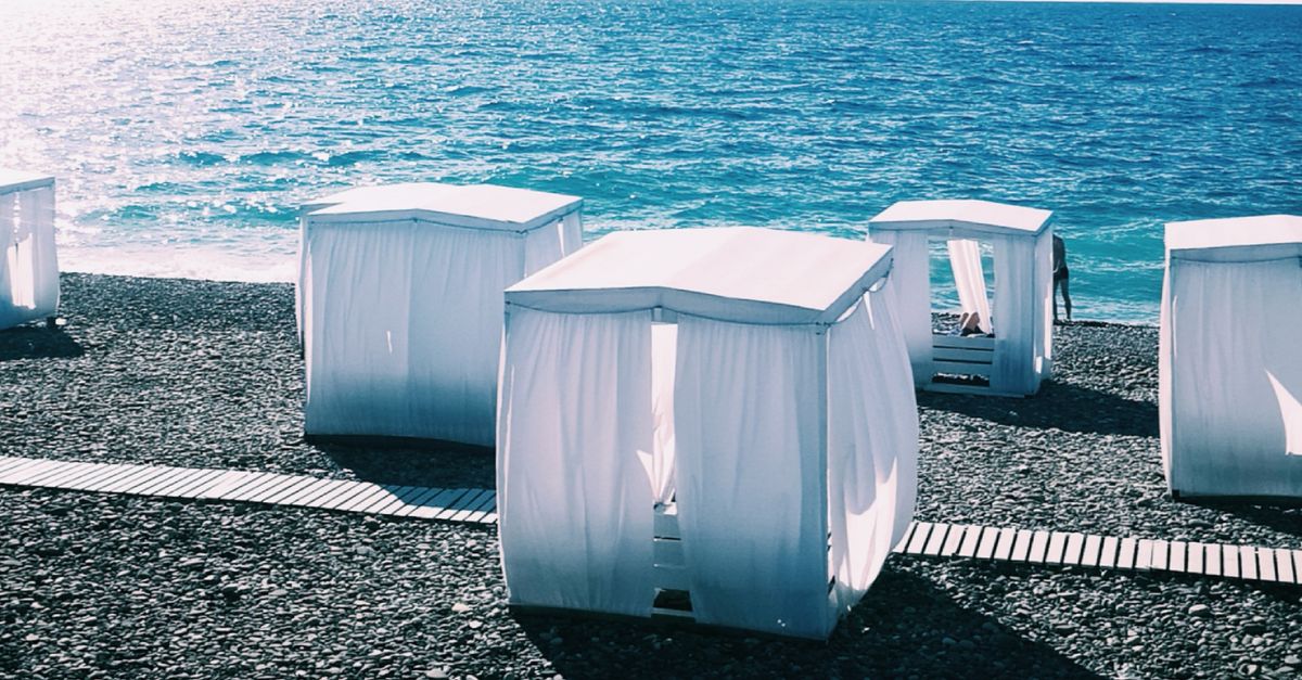 White cabanas on a rocky beach by the Black Sea in Sochi. Bright sunlight and clear waters.
