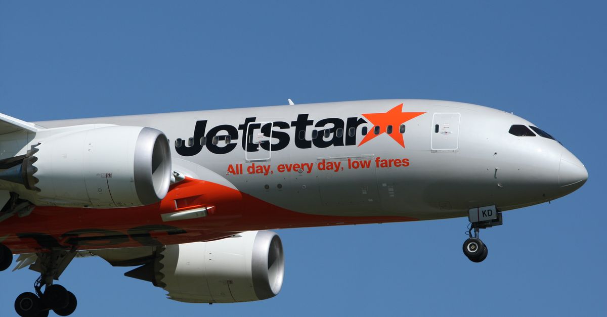 Close-up of a Jetstar aircraft approaching for landing against a clear sky.