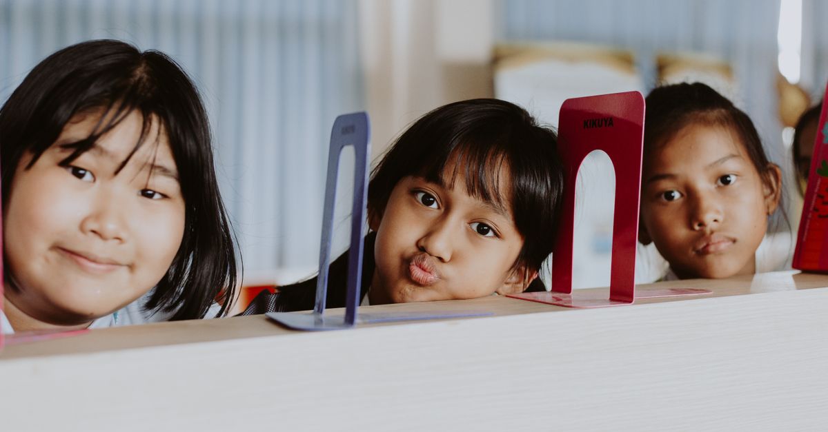 Three children engaging in playful expressions during class in a school setting.
