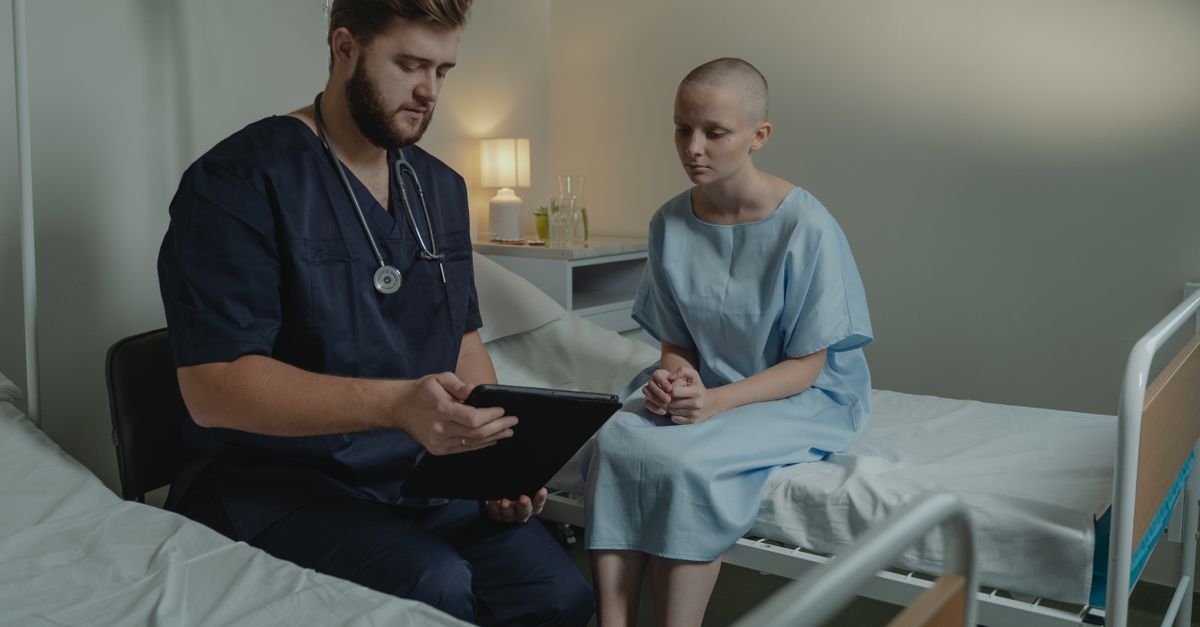 A doctor in a hospital ward consulting a patient with a digital tablet.