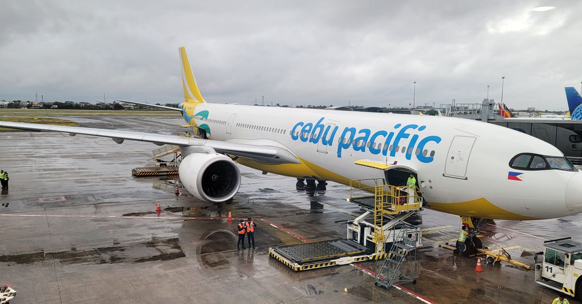 A Cebu Pacific airplane on a cloudy day at an airport terminal.