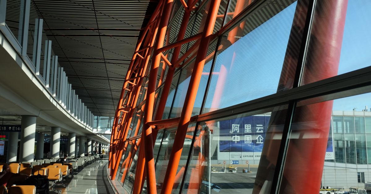 Large airport terminal with unique orange steel beams and expansive glass windows showcasing a bright day.