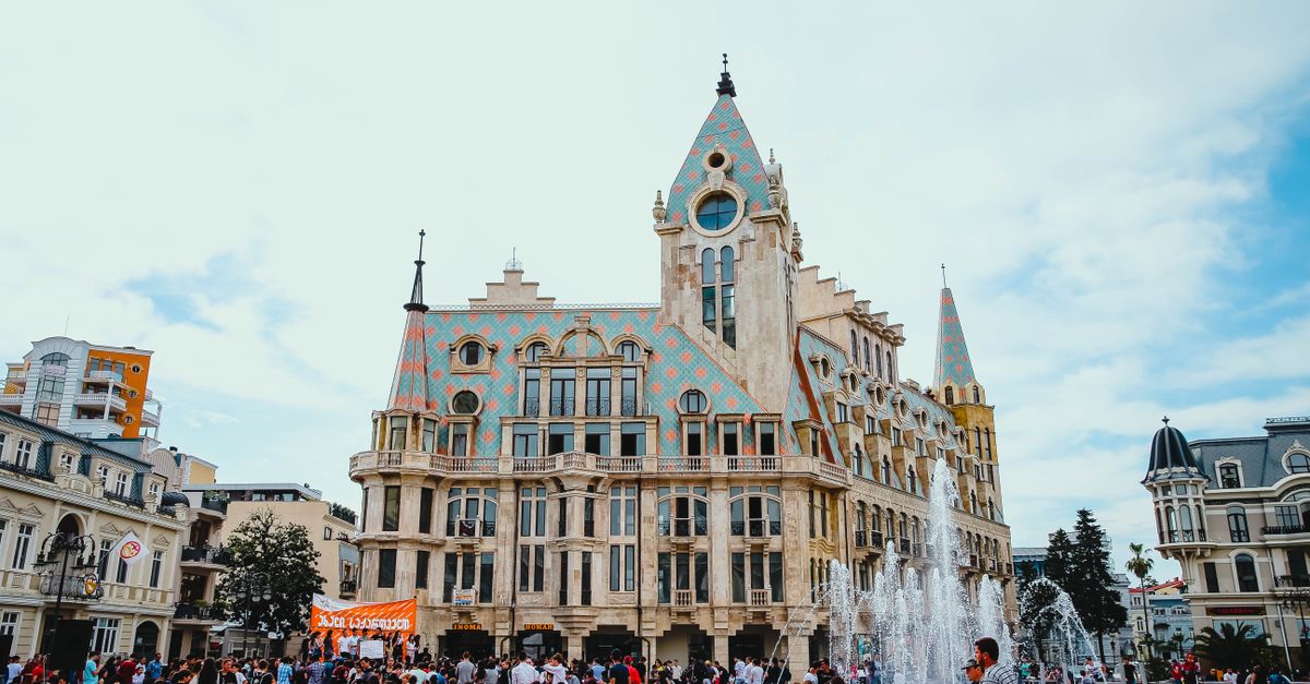 People enjoying a lively day at Europe Square, Batumi, with a stunning architectural backdrop and fountain display.