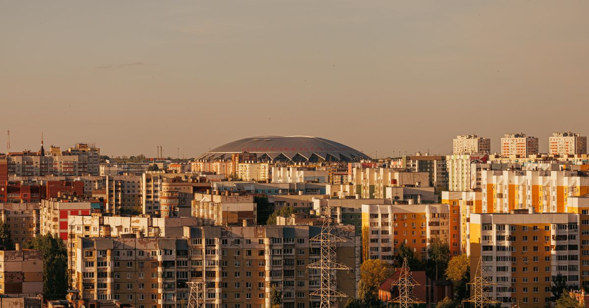 Aerial view of a cityscape with a large stadium and residential area at sunset.
