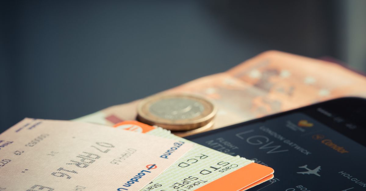 Airline ticket with euro coins and smartphone displaying flight details.