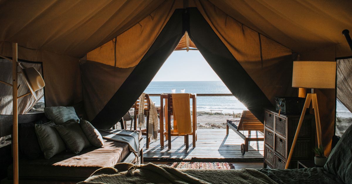 Interior of comfortable camping room with wooden furniture and bed with pillows on seashore