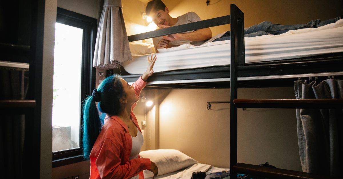 Young couple enjoying a cozy stay in a hostel bunk bed room, perfect for budget travel and bonding.