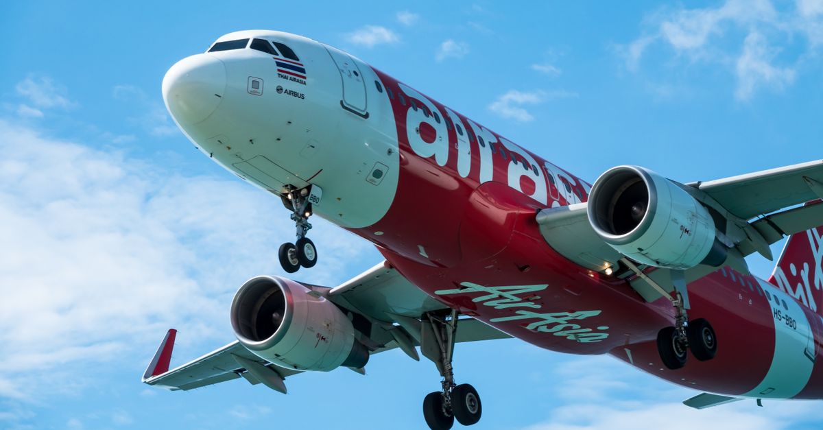 Close-up of a red and white airplane flying in a blue sky, captured from below.