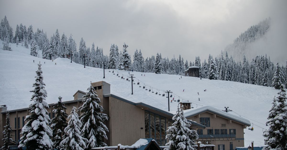 Scenic view of a snow-covered ski resort with skiers on the slope at Snoqualmie Pass.
