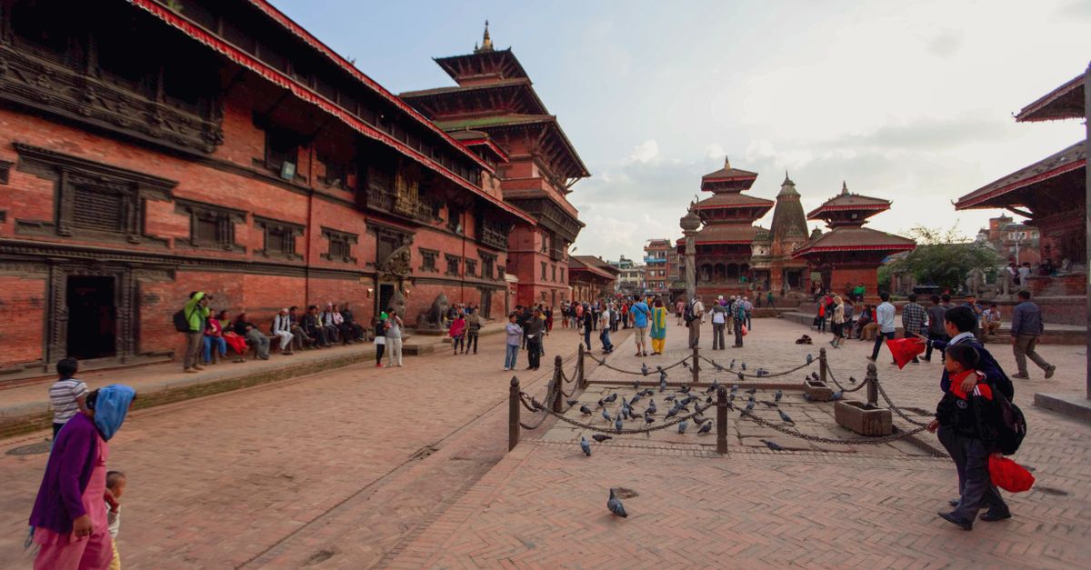 Patan Durbar Square with locals and tourists in Kathmandu, showcasing traditional architecture.