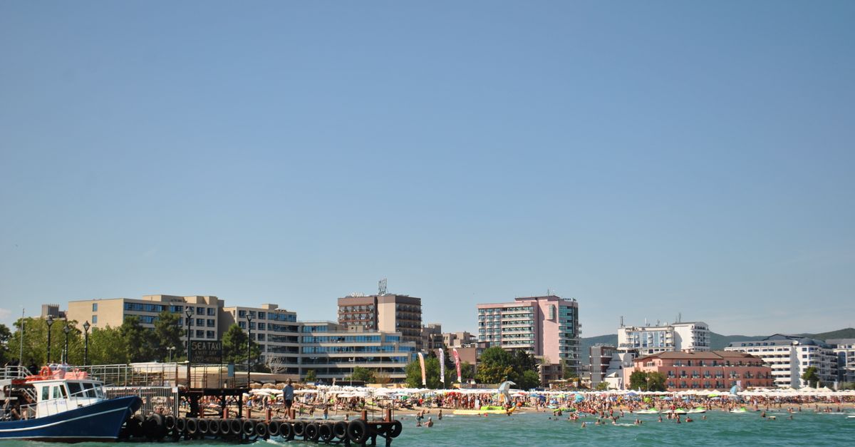 Sunny day at a bustling beach with a lively skyline and turquoise sea, perfect for summer tourism visuals.