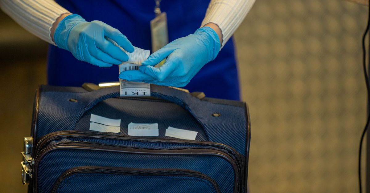 Close-up of airport security process with gloved hands inspecting luggage tags.