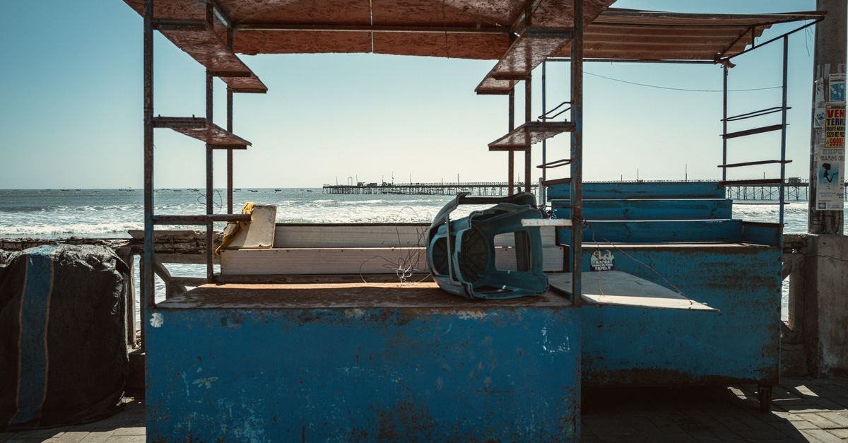 Rustic abandoned stalls on a deserted beach with ocean view, capturing solitude and decay.