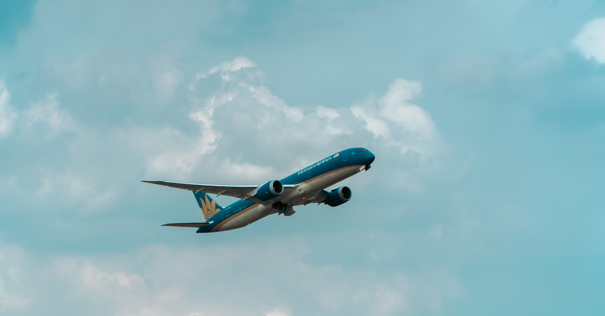 A commercial airplane flying through a cloudy blue sky, showcasing aviation travel.