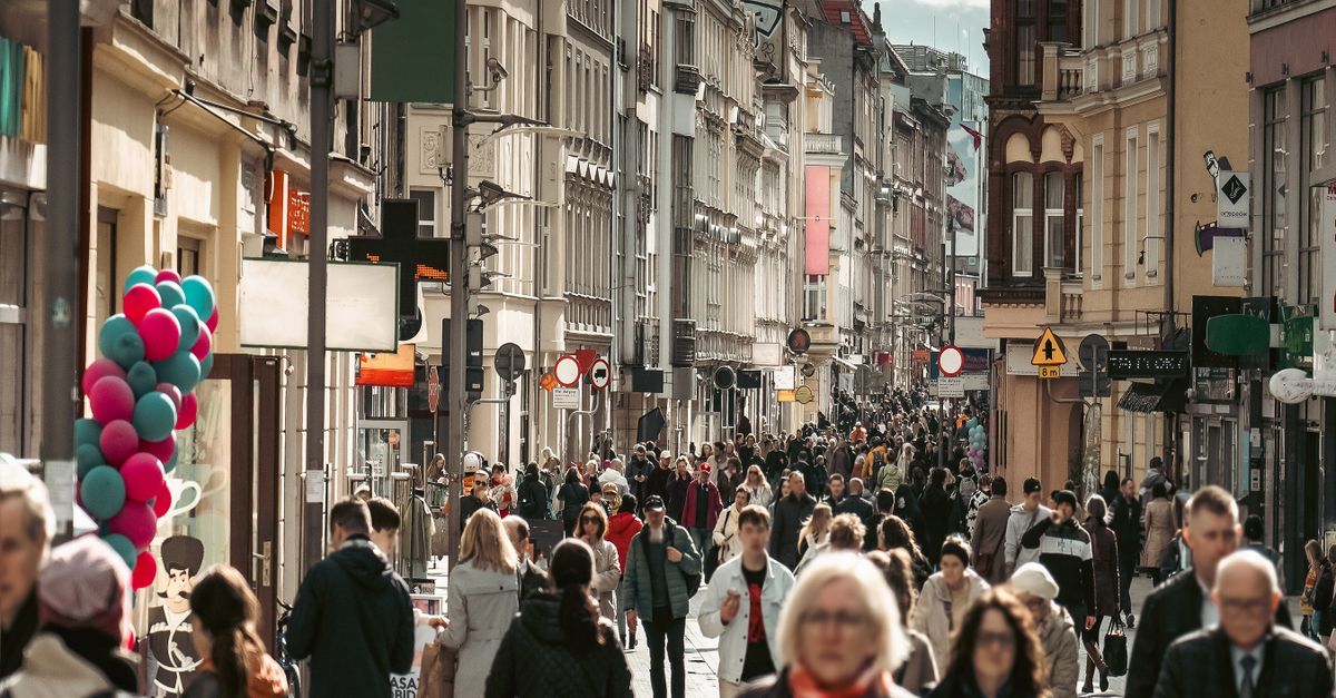Bustling downtown Poznań street with diverse crowd and historic buildings.