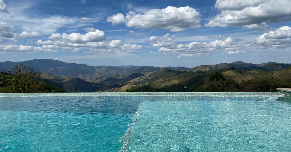 Stunning infinity pool with panoramic mountain views under a bright sky.