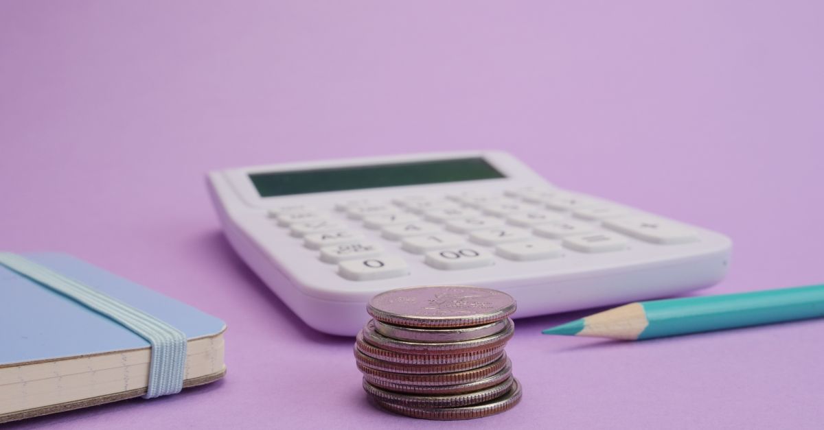 Calculator, coins, and stationery symbolize budgeting and finance on a pastel purple backdrop.