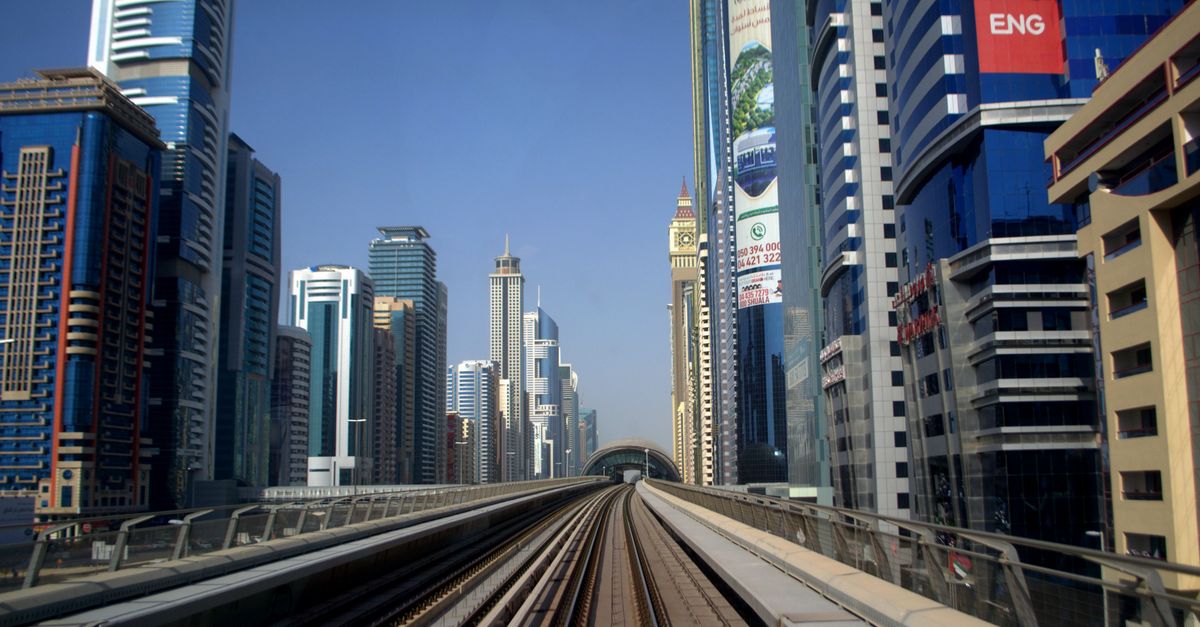 Dynamic shot of Dubai Metro with futuristic skyline in the background, showcasing urban transportation and architecture.