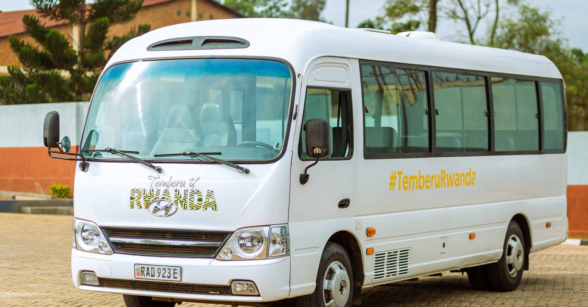 A white tour bus promoting TemberuRwanda, parked outdoors on a sunny day.