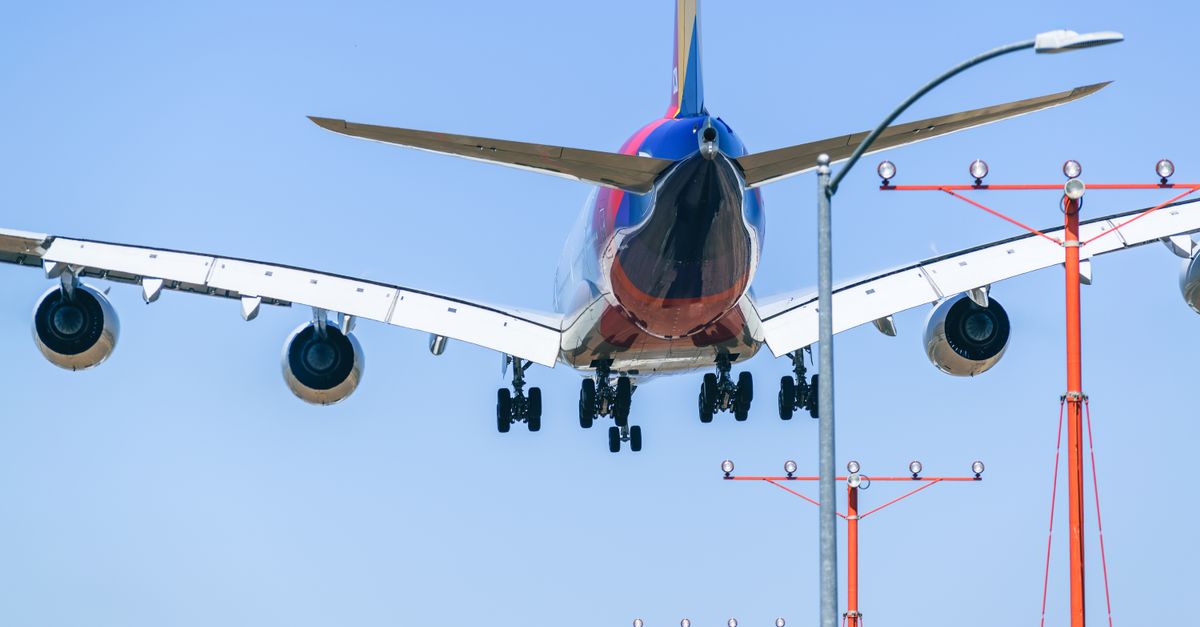 Passenger airplane approaching runway during daytime landing with clear blue sky backdrop.