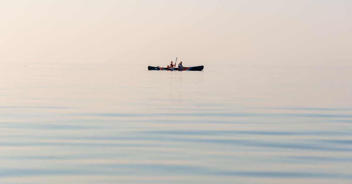 Peaceful scene of two people kayaking on calm waters, emphasizing tranquility and nature.