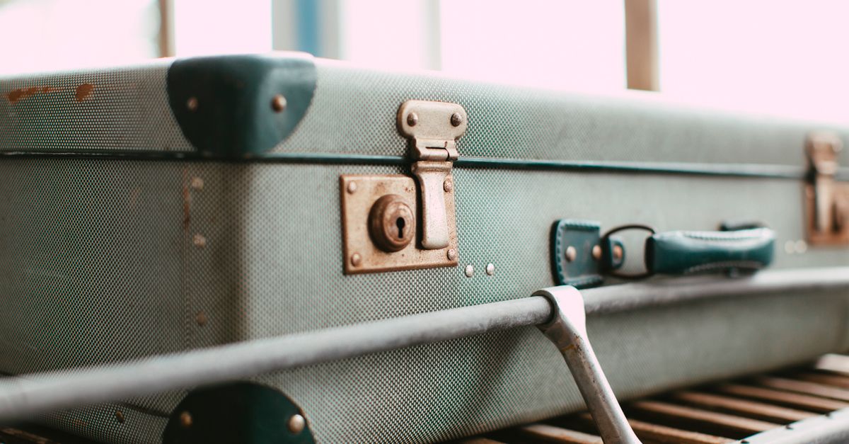 Close-up of a vintage green suitcase with metal hardware, conveying a retro travel feel.