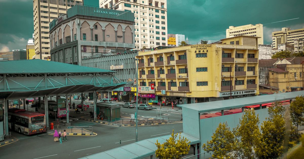 A bustling urban intersection with Lavana Hotel, bus station, and vibrant street life.