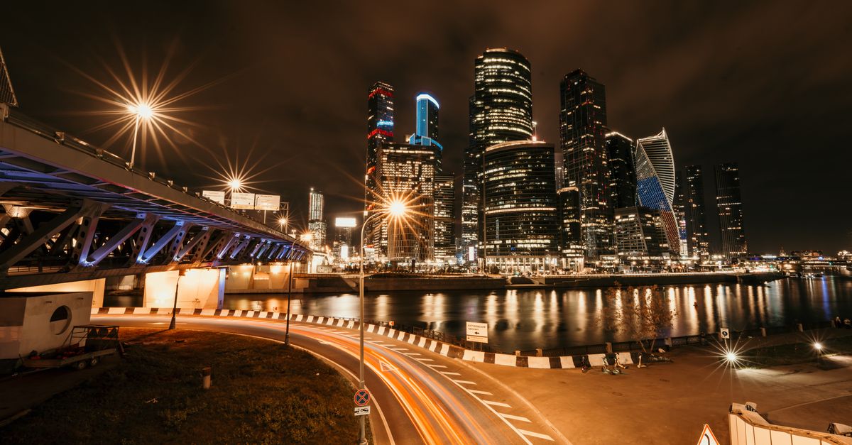 Stunning nighttime cityscape featuring illuminated skyscrapers and a bridge with glowing streetlights.