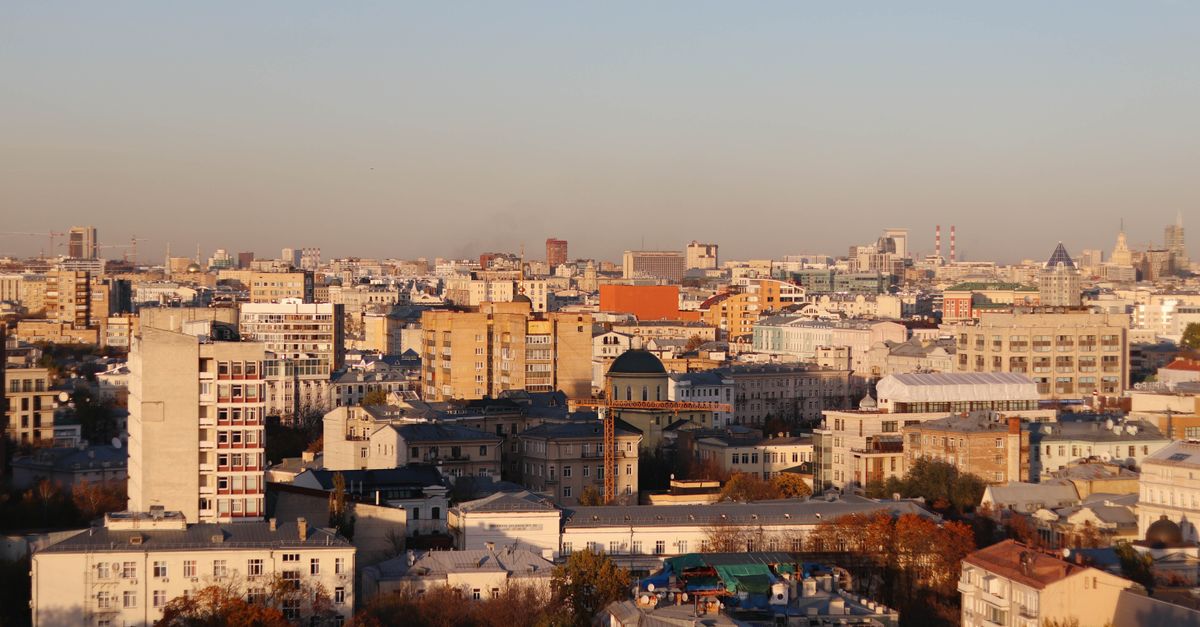 Aerial view of a sprawling urban cityscape under a clear sky with warm sunset hues.