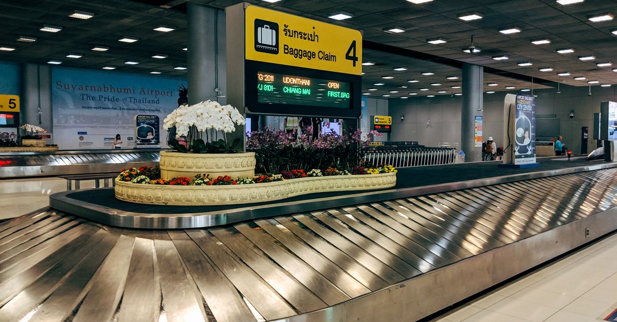 Modern baggage claim area at Suvarnabhumi Airport in Bangkok with luggage carousel and signage.