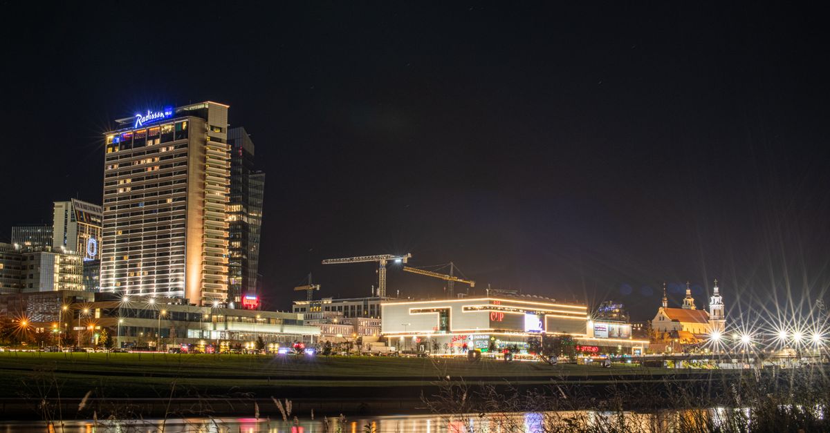Stunning night view of Vilnius, Lithuania, showcasing city lights and modern architecture along the Neris River.