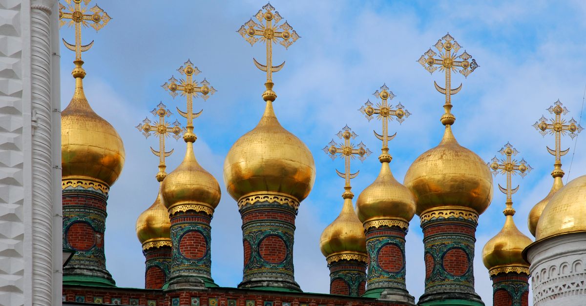 Close-up of the iconic golden domes and crosses of a Russian Orthodox church against a blue sky.