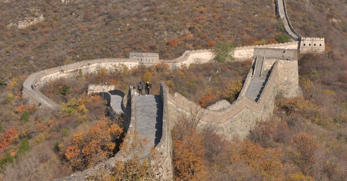 Aerial view of the Great Wall of China with autumn foliage, showcasing historical architecture.