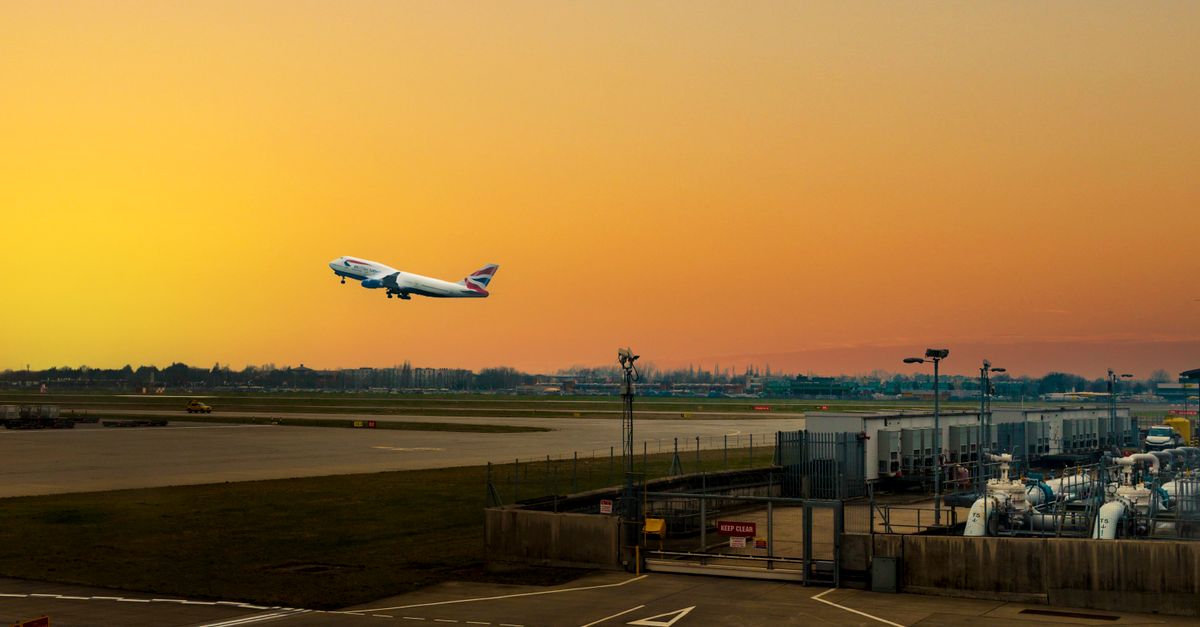 Airplane ascending during sunset at Heathrow Airport, capturing the vibrant sky.